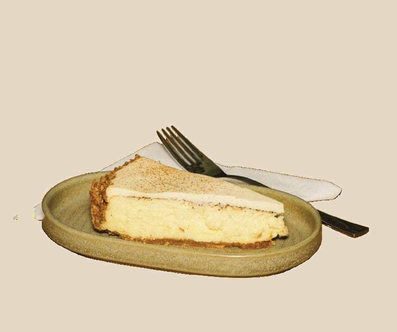En bit Forum-ostekake med kaffekrydder, på et grønt fat med gaffel