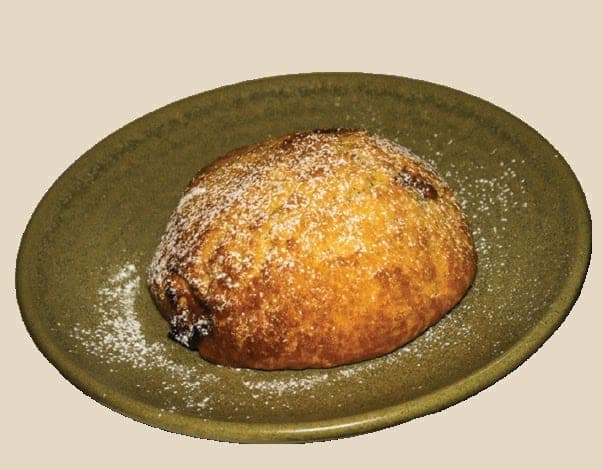 Brunostscone med melis, servert på et olivengrønt fat